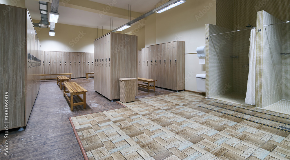 Public shower interior with everal showers, toilet sink and lockers in locker room in luxury