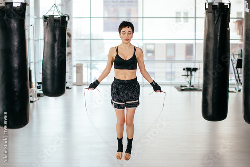 nice female with short black hair is jumping with skipping rope at gym.jumping rope techniques. cardiovascular workout © alfa27