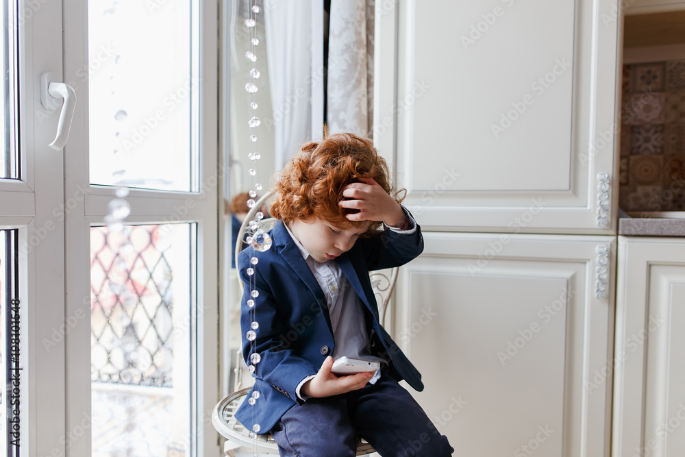 Little redhead boy uses a smartphone