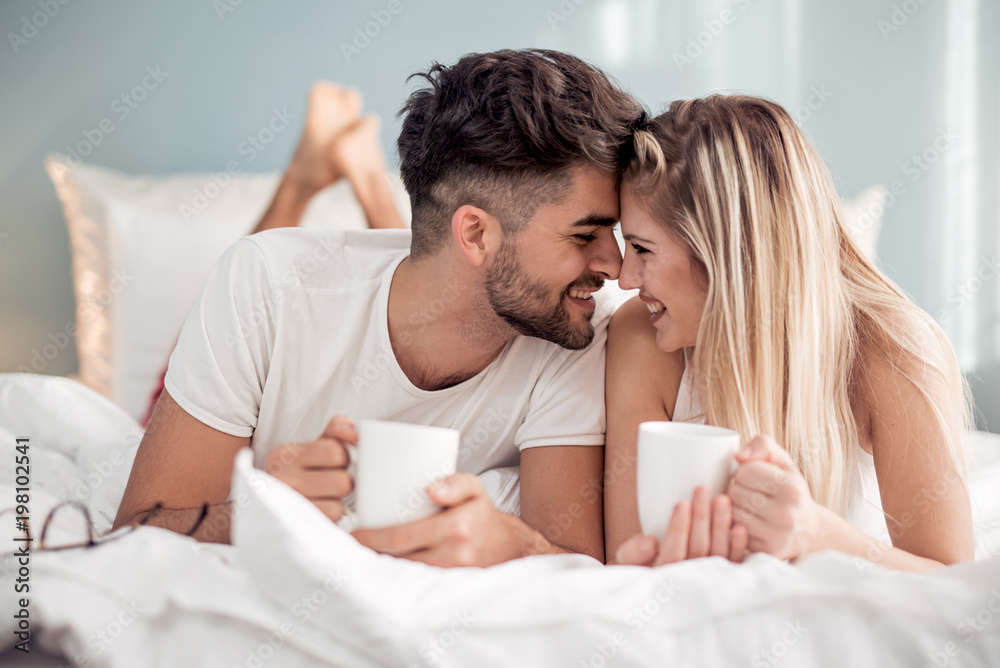 Picture of young couple drinking coffee in bed - obrazy, fototapety, plakaty 