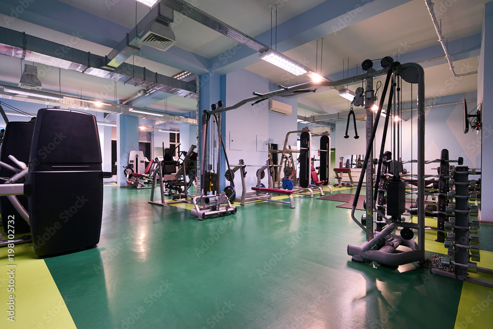 Modern gym interior with sports equipment. Fitness club with training exercise equipments  - obrazy, fototapety, plakaty 