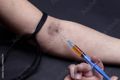 Injecting drugs with a syringe into an arm vien