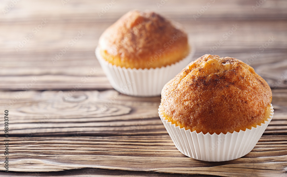 Classic muffins on a wooden old background in a white wrapper. Classic muffins on a wooden old background in a white wrapper.