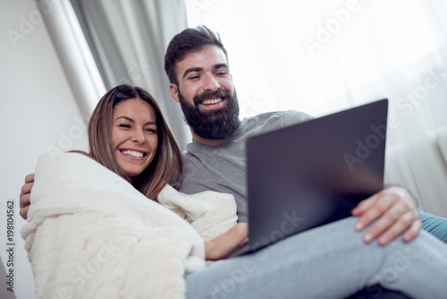 Young couple relaxing on sofa with laptop in the living room