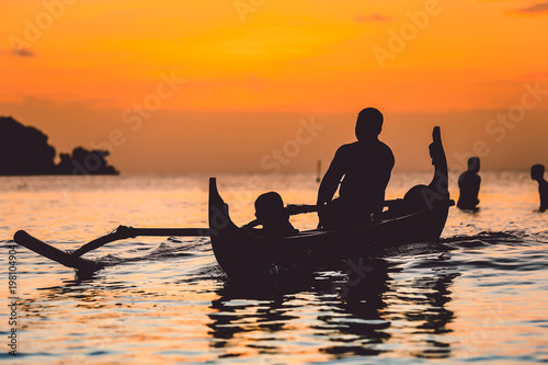 Silhouette of traditional fishing boat at sunset in Bali, Jimbaran beach
