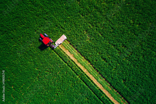 Tractor mowing green field, aerial view
