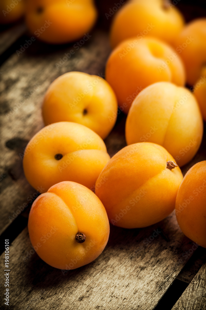 Apricots fresh arrangement close up in old wooden box on bright light in studio Apricots fresh arrangement close up in old wooden box on bright light in studio
