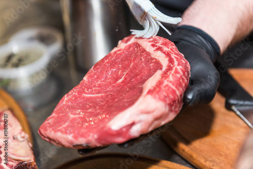 The hands of the chef lubricate raw meat photo