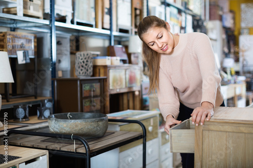 Woman buyer standing in furniture shopping room near chest of drawers