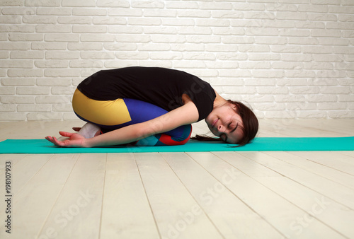 Woman doing yoga and fitness exercises stretching her body indoors