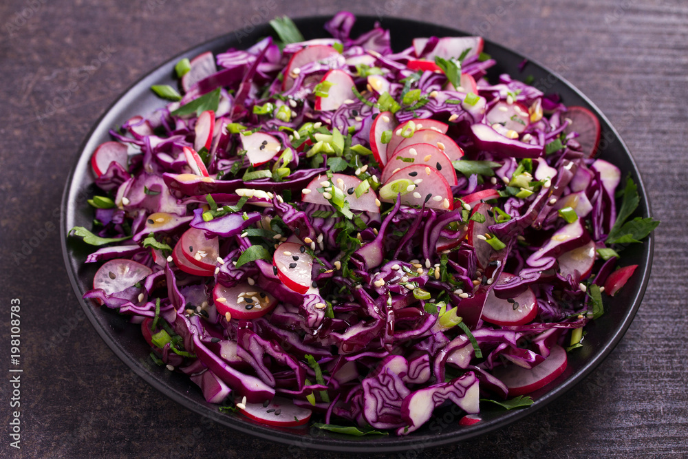 Plate of red cabbage, radish, chives, parsley and sesame seeds salad. Vegetarian or vegan healthy food concept Plate of red cabbage, radish, chives, parsley and sesame seeds salad. Vegetarian or vegan healthy food concept