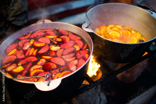 Hot gluhwein or mulled wine in a cauldron at fair, local treat, warm and spicy. A hot wholesome traditional citrus drink on fair. Vitamins in the winter festival.