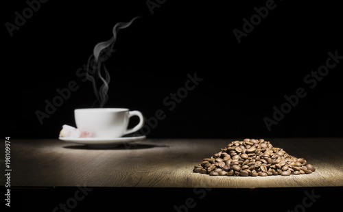 steamed coffee cup on the wood table with coffee beans stack