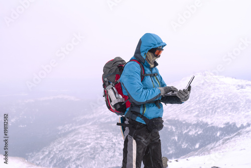 climber working with a laptop in winter on top of a mountain in extreme conditions