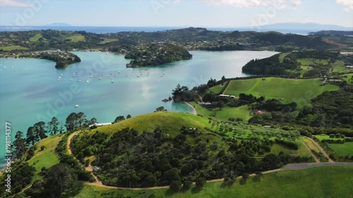Drone shot green hills and blue ocean with yachts in bay.