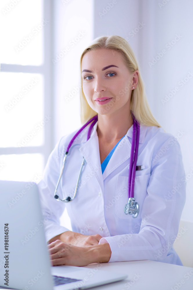 Female doctor sitting on the desk and working a laptop in hospital Female doctor sitting on the desk and working a laptop in hospital