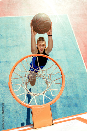 Young man jumping and making a fantastic slam dunk playing streetball, basketball. Urban authentic. © FS-Stock