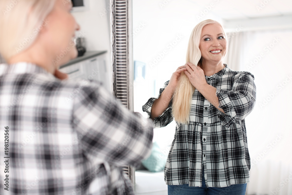 Mature woman looking in mirror at home Mature woman looking in mirror at home