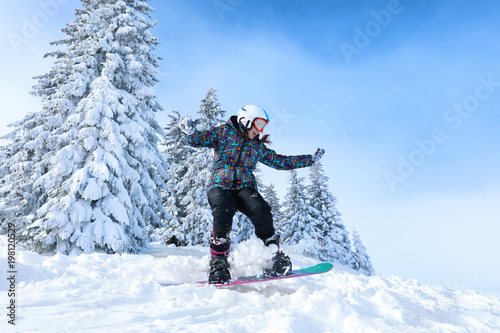Female snowboarder on ski piste at snowy resort. Winter vacation