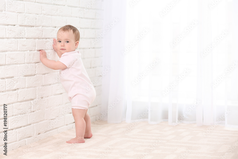 Cute baby holding on to wall indoors. Learning to walk Cute baby holding on to wall indoors. Learning to walk