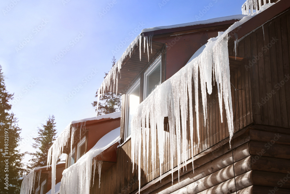 Obraz premium Wooden house with icicles on winter day