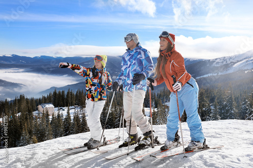 Fotografie Friends on ski piste at snowy resort. Winter vacation