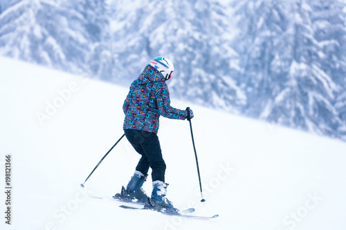 Woman skiing downhill at snowy resort. Winter vacation