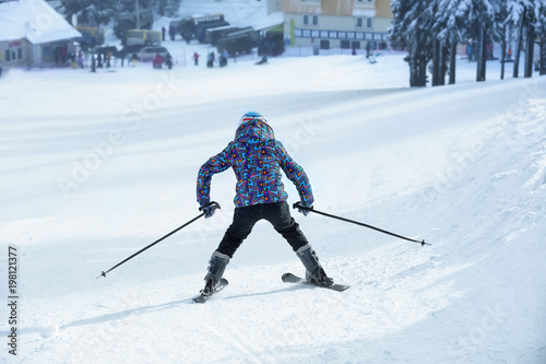 Woman on ski piste at snowy resort. Winter vacation