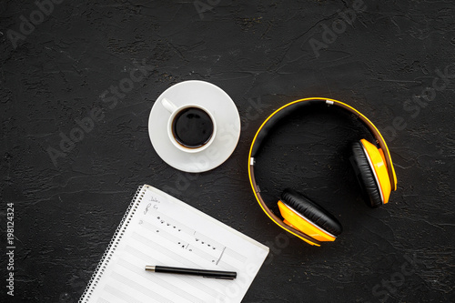 Composer office desk . Workplace of musician with headphones and notes black background top view mockup
