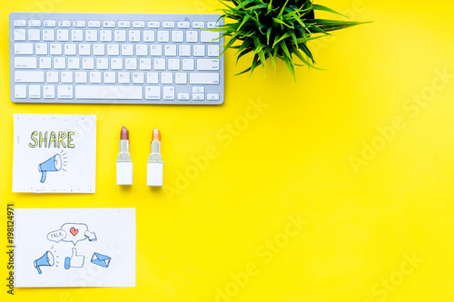 Beauty blogging concept. Work desk with keyboard, cosmetics and social media icons on yellow desk top view copy space