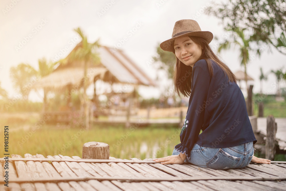 Happy asian woman sitting on bamboo table at rice farm in Thailand.
