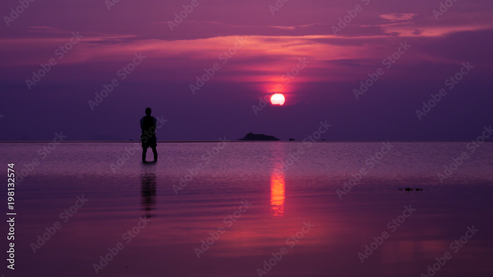 silhouette of man standing in sea at sunset