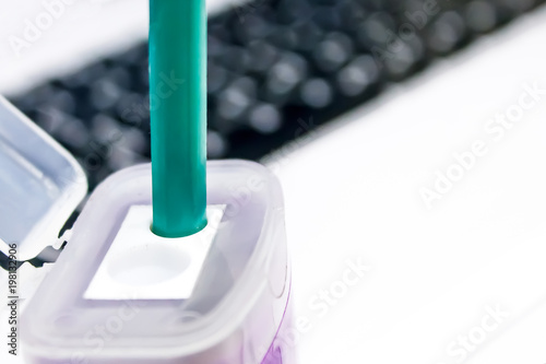 green pencil in a purple sharpener on laptop background