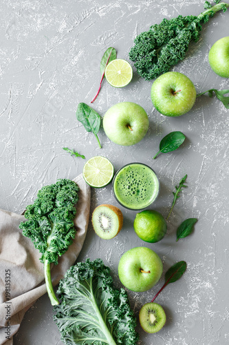Healthy green smoothie with fresh green fruits, kale and spinach on gray background, top view