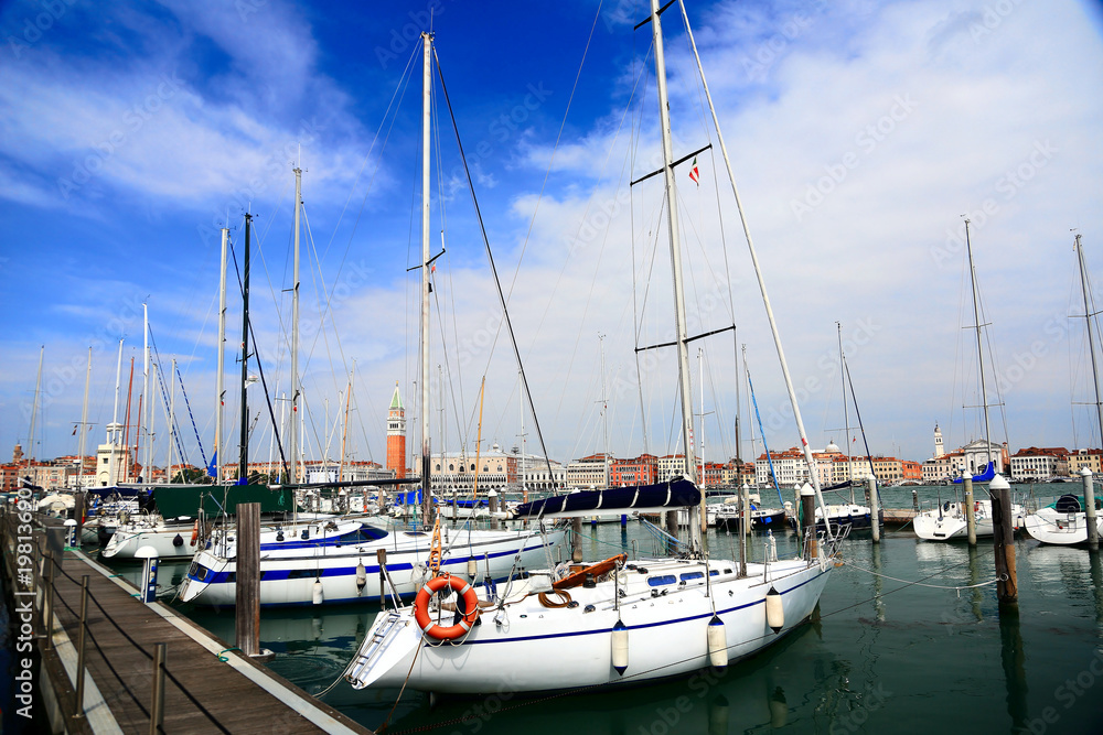 Boats parking by marina under blue sunny sky at San Giorgio Maggiore Island, Venice Italy