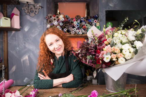 Valokuva portrait of saleswoman with ginger hair working with flowers in flower shop