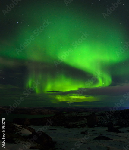 Northern Lights, polar lights above the hills and tundra bay in winter.