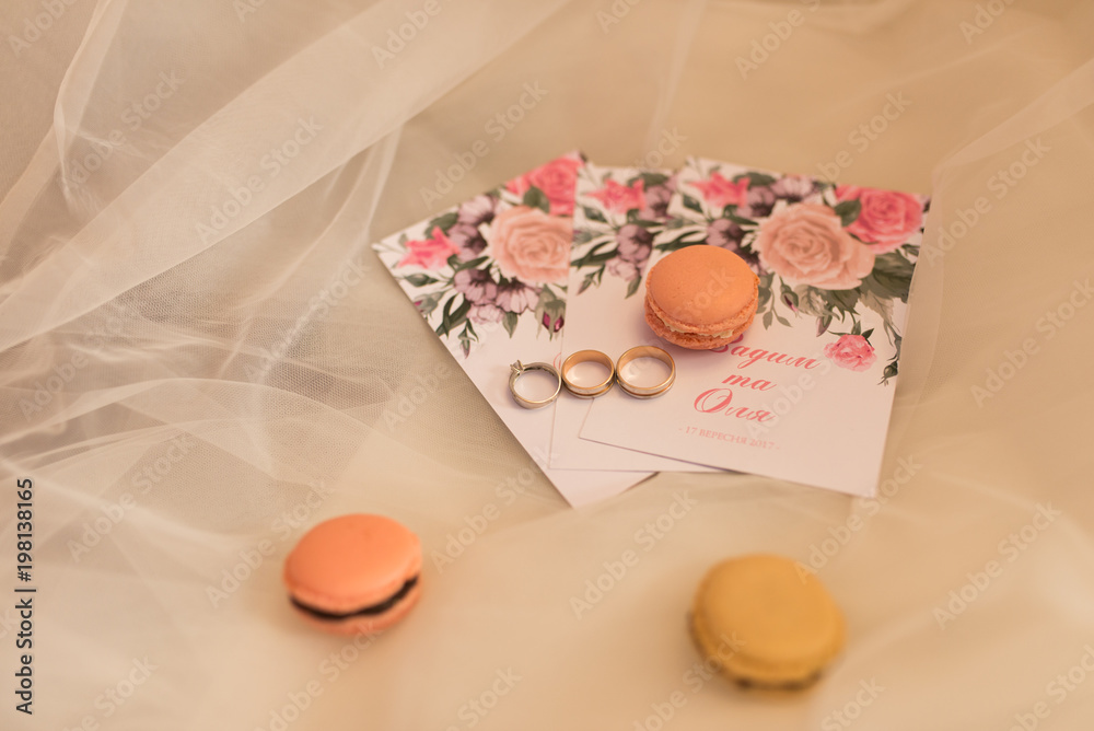 On the wedding invitation lying pastry macaroons and wedding rings. Wedding concept. On the wedding invitation lying pastry macaroons and wedding rings. Wedding concept.