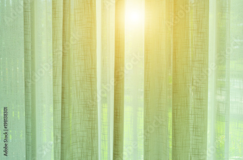 The sun shines through the translucent curtains.