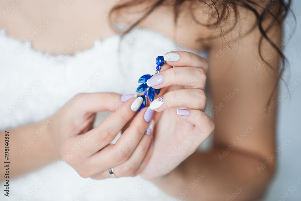 Women's wedding jewelry (earrings) in the hands of the bride, selective focus Women's wedding jewelry (earrings) in the hands of the bride, selective focus