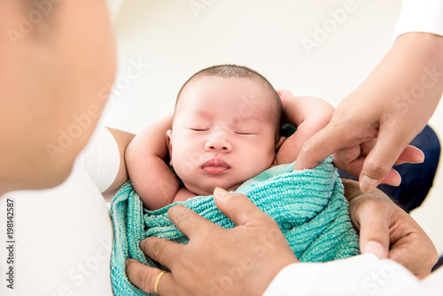 Adorable newborn baby sleeping in the arms of father