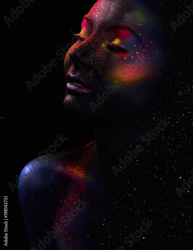 Glowing neon makeup with dramatic look in his eyes. Creative body art on the theme of space and stars. Amazing close-up portrait  glow in the dark makeup.