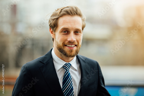 elegant blonde man in suit outside using his cellphone