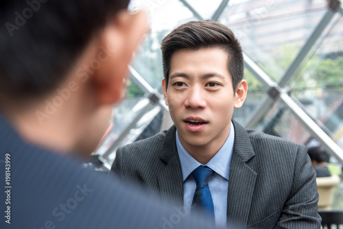 Young handsome Asian Chinese businessman talking to his partner
