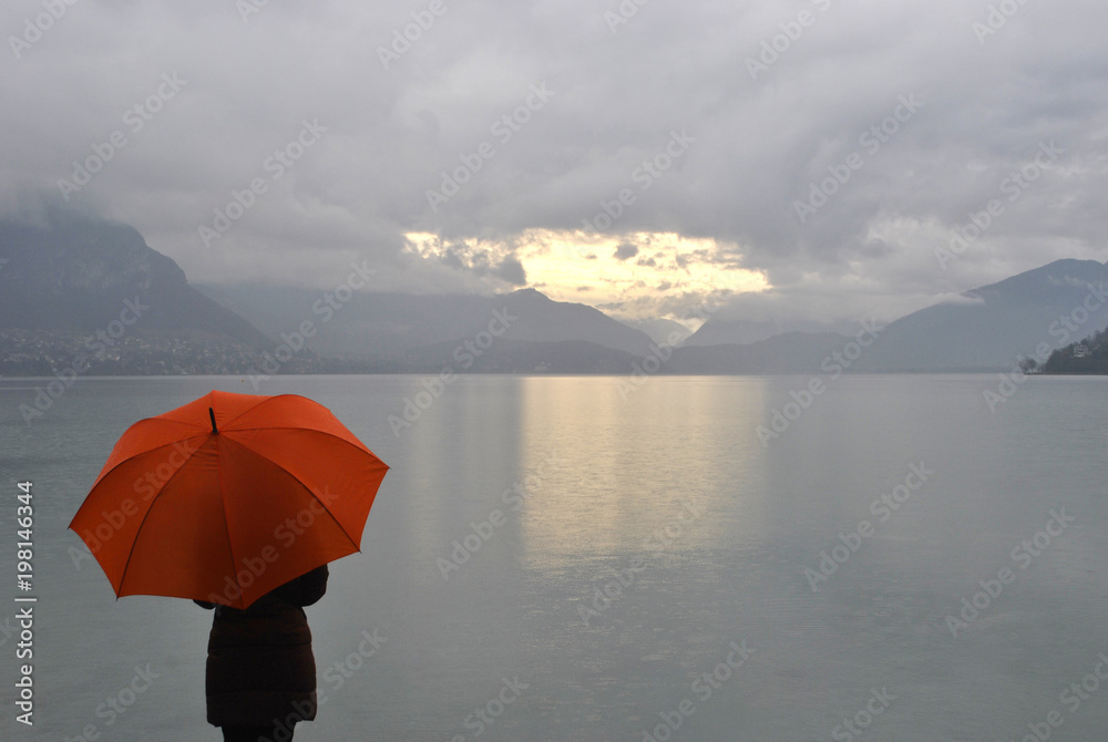 girl with umbrella meets sunrise on Lake Annecy in France