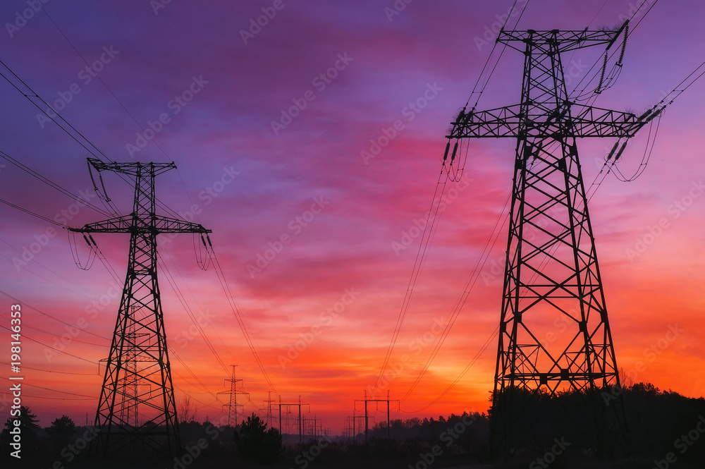 High-voltage power lines during fiery sunrise