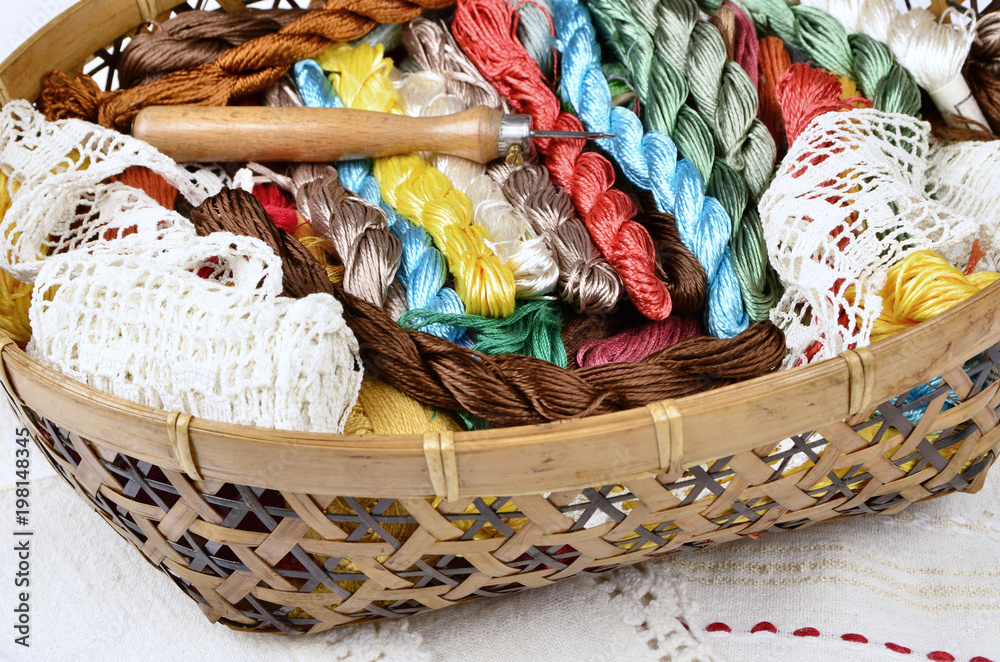 Vintage basket with sewing kit, multi-colored threads on fabric background,hand-knit lace