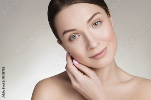 Close up of a beautiful brunette caucasian woman with fresh clean natural skin and soft smile on her face. Neutral, daily make up