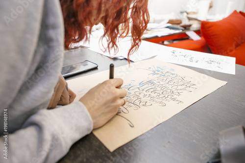 Woman make calligraphy writings, make art on a paper using pen brush and sign pen. Adult, old hands of a calligrapher woman. Lifestyle image of a design process photo