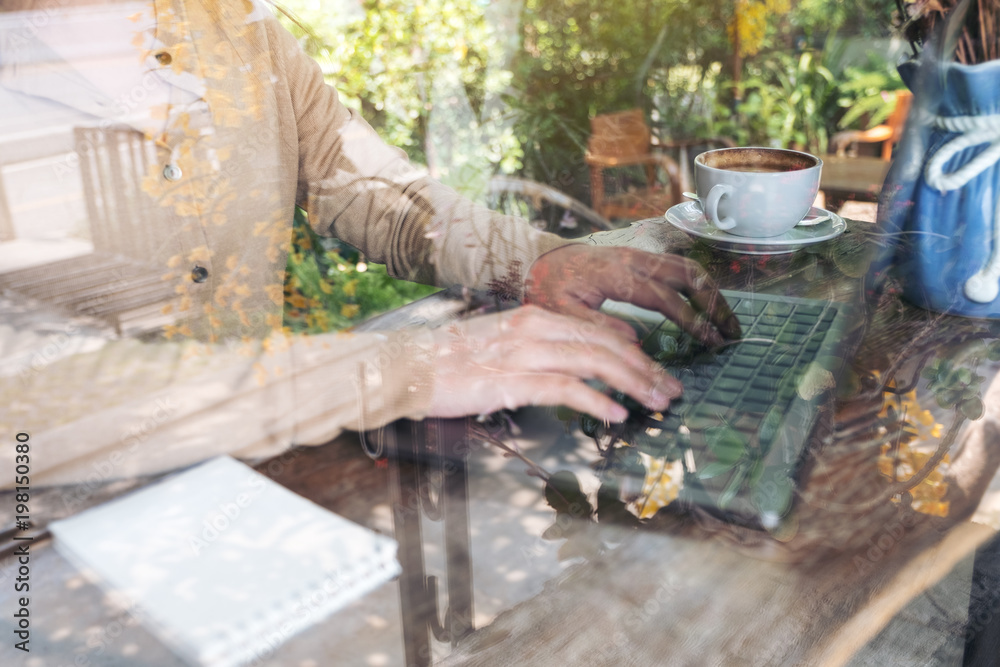 Closeup image of hands working and typing on laptop keyboard on wooden table in cafe